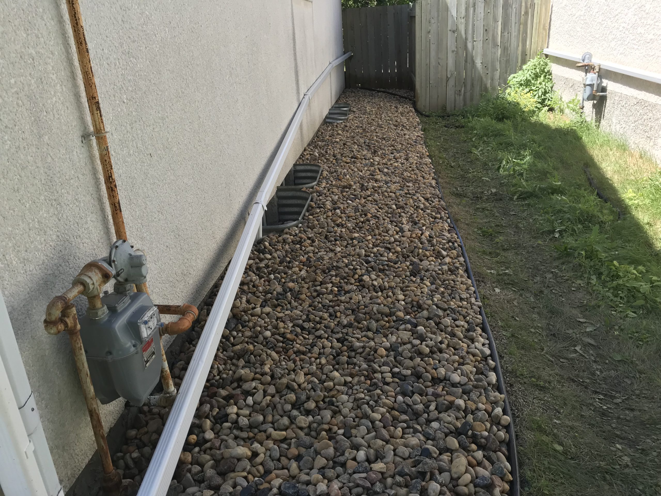 River rock installation along side foundation with proper drainage and clean edging