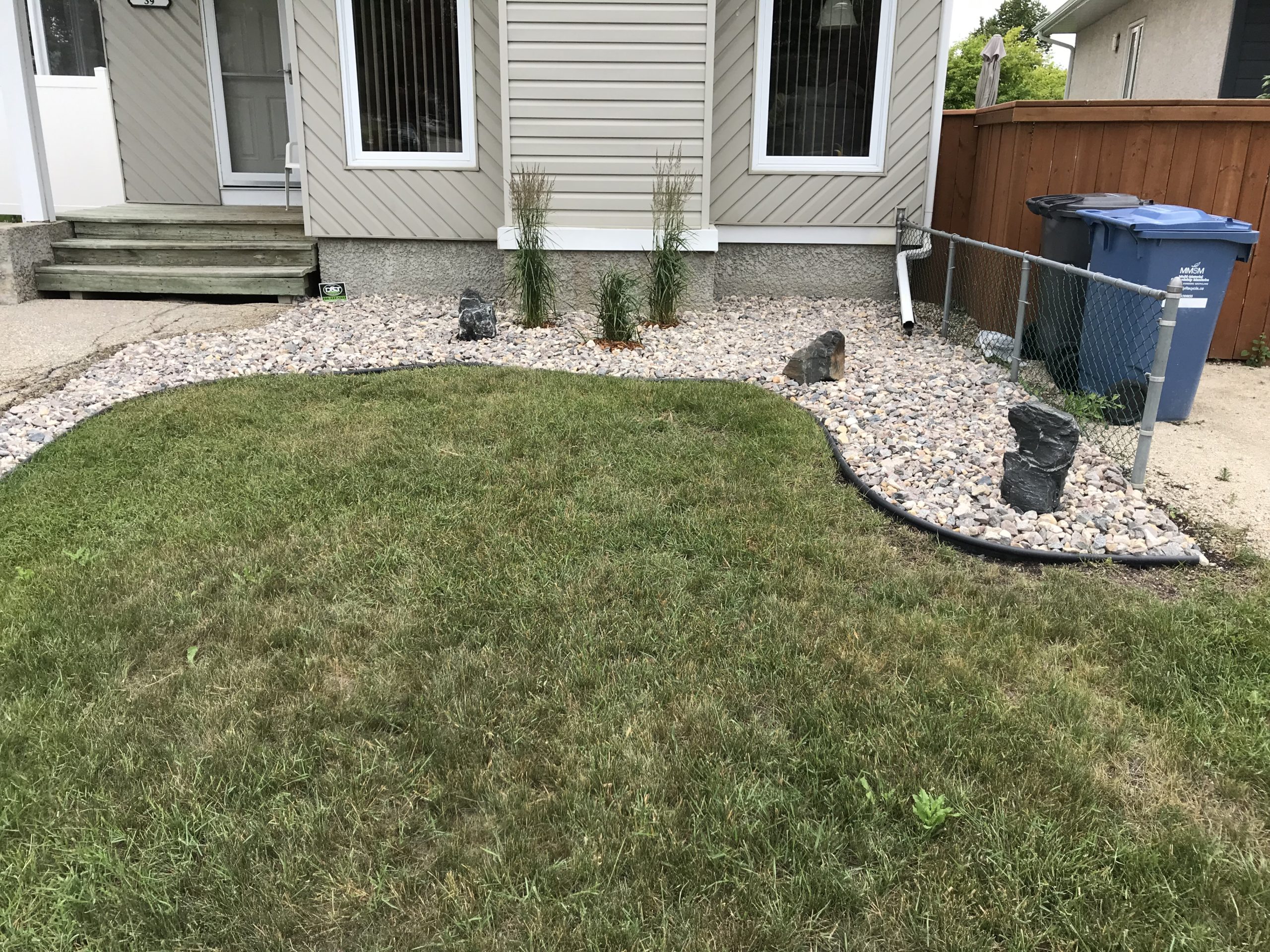 Complete rock landscaping renovation with ornamental grasses, boulders, and fresh edging