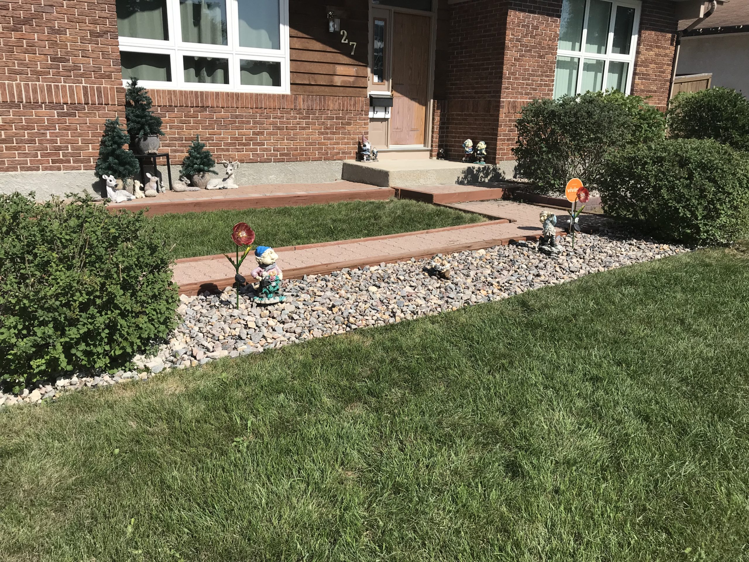 River rock border installed around front foundation bed with decorative accents