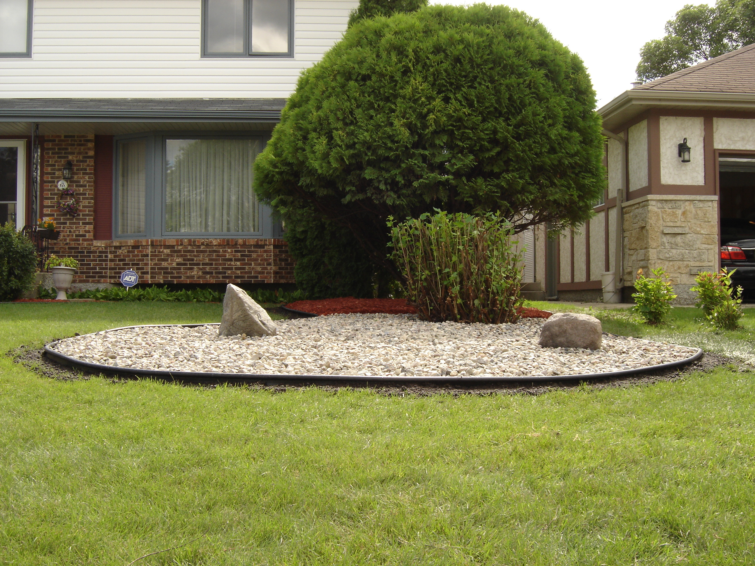 River rock tree ring with decorative boulders and professional edging installed
