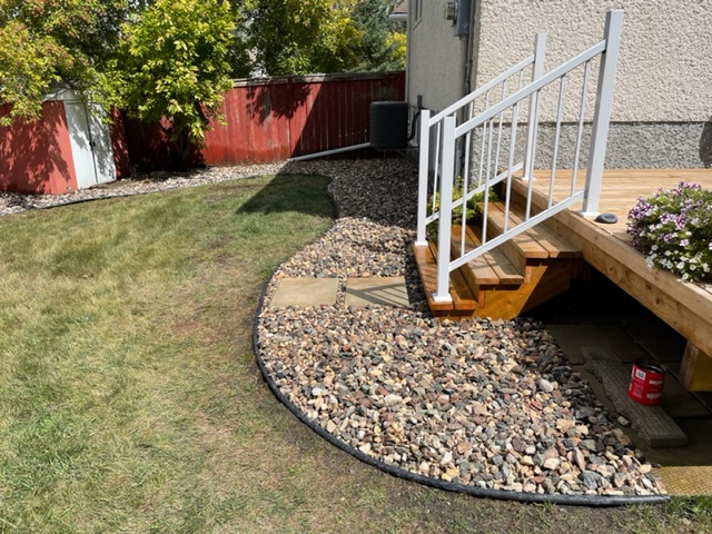 Rock bed with stepping stones installed around deck, connecting to back garden