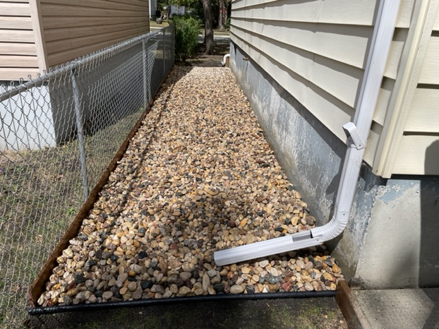 River rock pathway installed along side foundation with wood edging